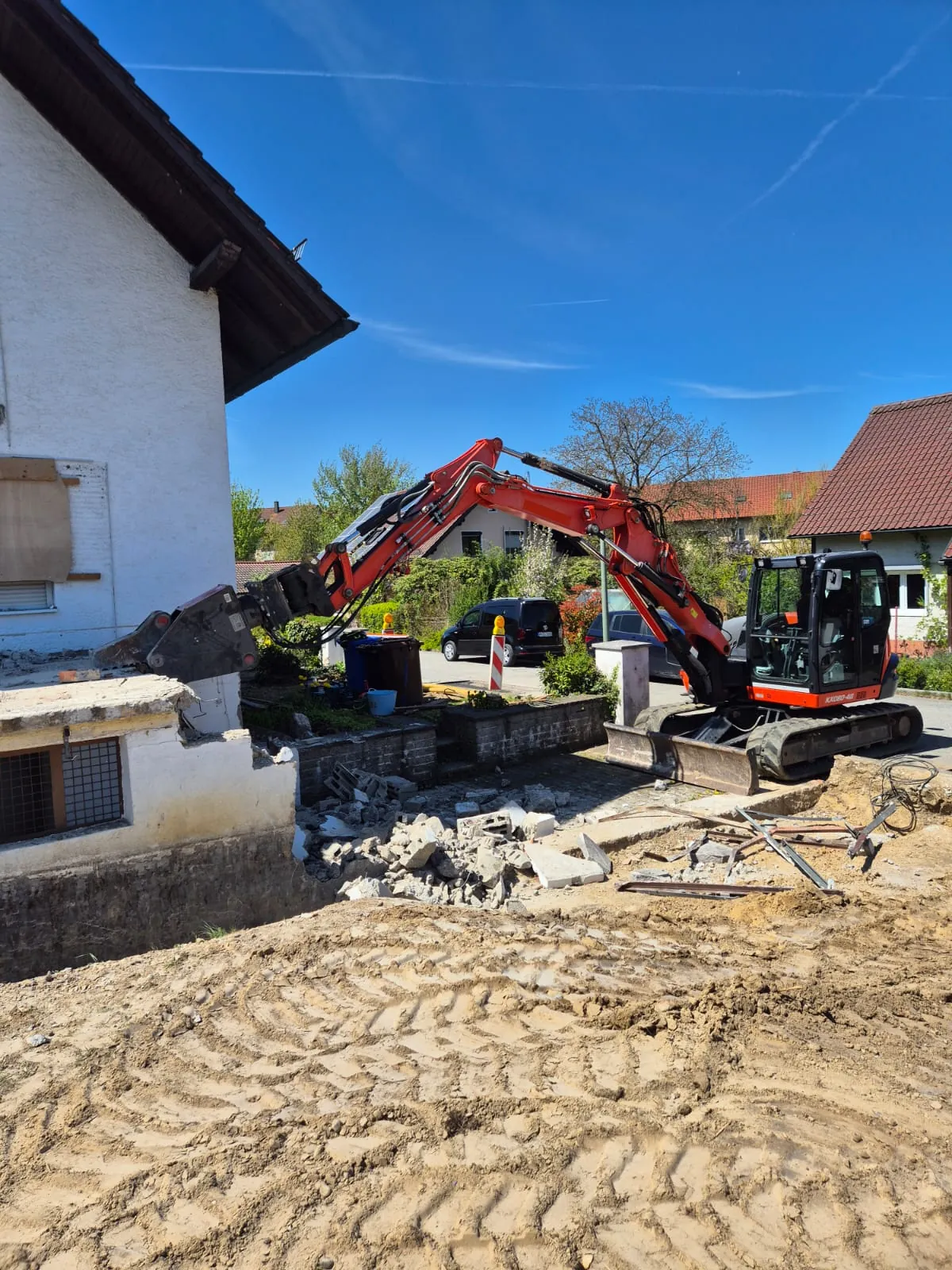 Kubota-Bagger vor dem Abrissschutt eines Wohnhauses