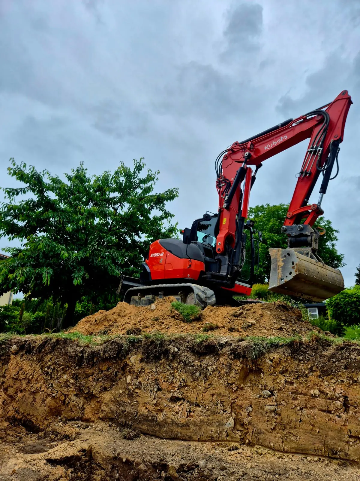 Kubota KX080 steht auf dem Aushub neben einer frisch gegrabenen Baugrube