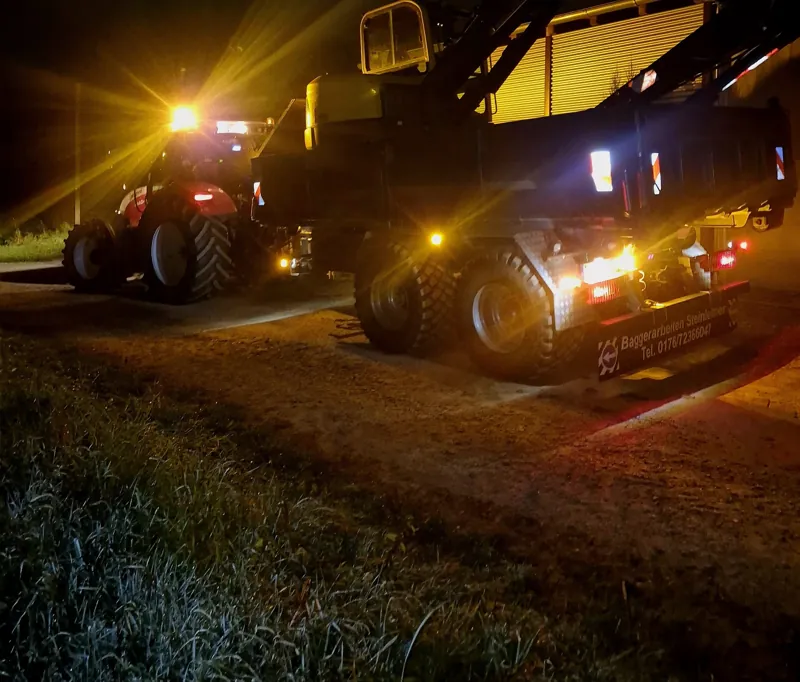 Traktor und Dumper mit Scheinwerfern bei Nacht